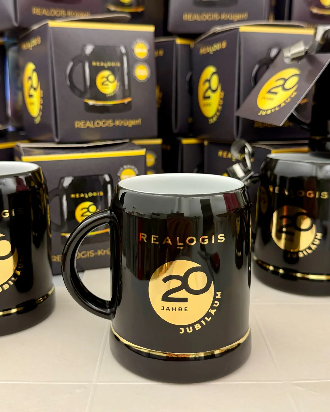 Schwarzes Realogis-Krügerl mit Logo in 24 Karat Gold