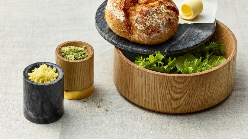 Holzschale mit Salat, Brot und Gewürzen